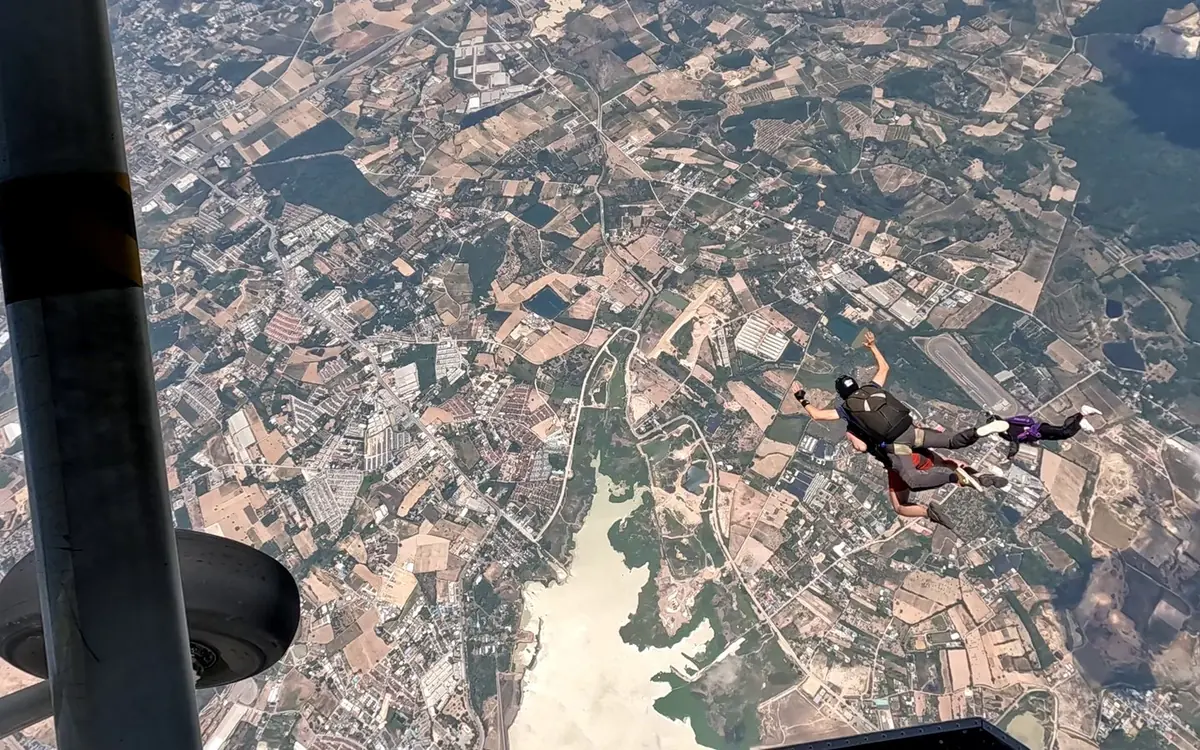 Der Blick aus dem Flugzeuginneren an einem Rad vorbei, mit Feldern und einer Flussmündung weit unten