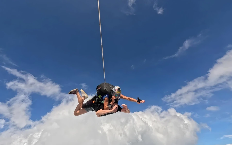 Ein einzelnes Tandempaar weit entfernt über einer flachen Wolkenschicht, Ausziehleine draußen
