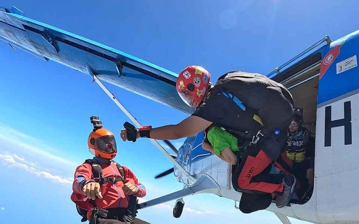 Ein Tandempaar verlässt die Flugzeugtür, die Tragfläche darüber und die Küste weit unten